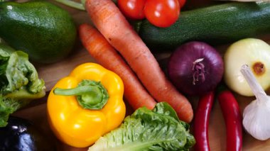 Mutfak masasında yavaş çekimde yakalanan çeşitli sağlıklı sebzeleri kapatın. Doğal beslenme konsepti..