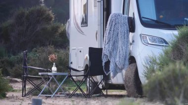 İnsanların doğanın tadını çıkarması için masalı ve sandalyeli bir karavan. Doğada kamp yapmak. Karavan tatili. Mobil evle seyahat etmek.