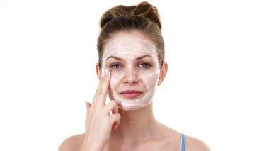 Maske takan genç bir kadın yüzüne nemlendirici krem sürüyor. Cilt nemlendiricisine dikkat eden bir kız. Cilt bakımı.