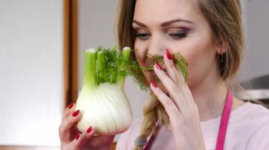 Çiğ sebze rezenesi tutan ve kokusunu alan mutlu genç bir kadın. Doğal organik sağlıklı gıda konsepti.
