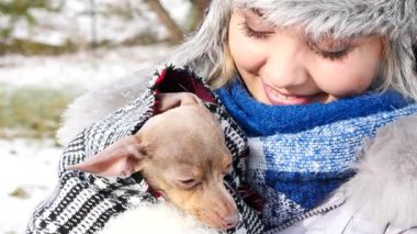 Köpeğiyle oynayan genç bir kadın, pinscher ratter prazsky krysarik, kış havasında dışarıda. Dişi köpek yavrusuna sevgiyle sarılıyor..