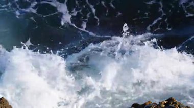 Büyük dalgalar kayalıklara çarpıyor. Ağır çekim. Yukarıdan görüntüle