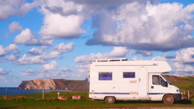 Kuzey İspanya 'nın Asterias sahilindeki Verdicio plajında kamp yapan bir kamp aracı. Cape Penas uçurumu uzakta. Karavanla git..