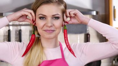 Neşeli kadın kırmızı kırmızı biber küpeleriymiş gibi davranarak eğleniyor. Sağlıklı sebze, diyet yiyecek konsepti.