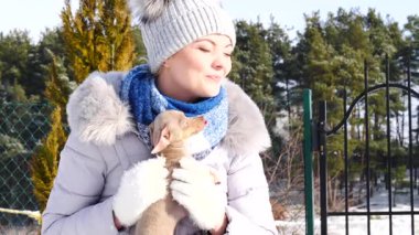 Genç bir kadın köpeğiyle oynuyor, pinscher ratter prazsky krysarik, kış havasında açık havada..