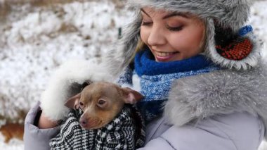 Köpeğiyle oynayan genç bir kadın, pinscher ratter prazsky krysarik, kış havasında dışarıda. Dişi köpek yavrusuna sevgiyle sarılıyor..