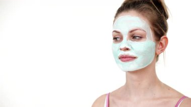 Yüzünde beyaz yeşil çamur maskesi olan genç bir kadın. Genç kız yağlı cildiyle ilgileniyor, gözenekleri temizliyor. Güzellik tedavisi. Cilt bakımı.