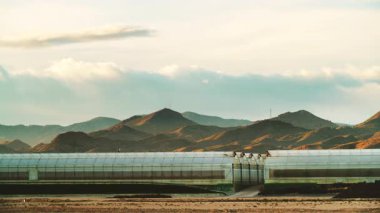 Akşamları, ticari seralarla birlikte kıyı manzarası üzerinde hareket eden bulutların hızlanması. Endüstriyel tarım. Murcia bölgesi, İspanya.