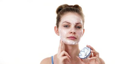 Maske takan genç bir kadın yüzüne nemlendirici krem sürüyor. Cilt nemlendiricisine dikkat eden bir kız. Cilt bakımı.