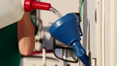 Karavan su deposunu huni kullanarak dolduran bir kadına yaklaş. Karavanla seyahat ediyorum. Karavan tatili.