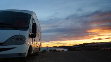 Gün batımında deniz kenarında kamp yapan bir karavan. Karavanla seyahat ediyorum. Karavan tatili. Doğa ve faaliyetler.