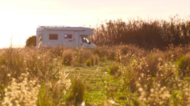 Kamp aracı, İspanya 'nın güneşli bir gününde sahildeki çayır arazisinde kamp yapıyor. Karavanla seyahat ediyorum. Karavan tatili.