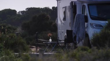 İnsanların doğanın tadını çıkarması için masalı ve sandalyeli bir karavan. Doğada kamp yapmak. Karavan tatili. Mobil evle seyahat etmek.