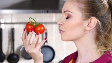 Küçük vişneli domates yiyen, sağlıklı yemek yiyen ve diyet yapan neşeli kadın..