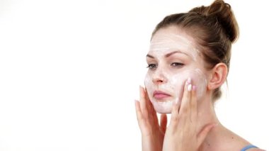 Maske takan genç bir kadın yüzüne nemlendirici krem sürüyor. Cilt nemlendiricisine dikkat eden bir kız. Cilt bakımı.