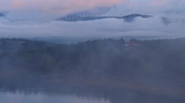 Sabah manzarası. Vadinin üzerinde sis ve tepede bulutlarla kaplı rüzgar türbinleri. Palencia, Kastilya ve Leon bölgesinde Aguilar de Campoo, Kuzey İspanya.