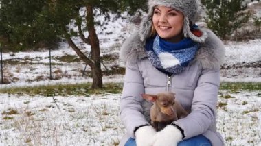 Genç bir kadın köpeğiyle oynuyor, pinscher ratter prazsky krysarik, kış havasında açık havada..