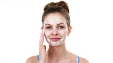 Maske takan genç bir kadın yüzüne nemlendirici krem sürüyor. Cilt nemlendiricisine dikkat eden bir kız. Cilt bakımı.