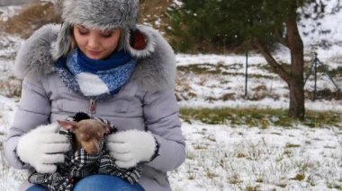 Küçük köpeğine bakan endişeli genç kadın pinscher ratter prazsky krysarik kış boyunca üşüyor.