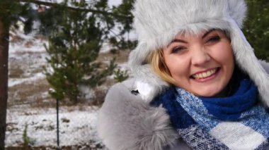 Kar yağışlı kış havasında kürk şapkalı ve eşarplı, sıcak bir ceket giyen genç ve şık bir kadın..