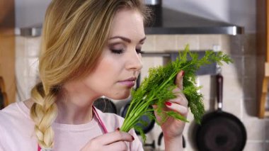 Yeşil dereotlu sebze kokusu alan genç ve güzel bir kadın. Sağlıklı gıda kokusu kavramı.
