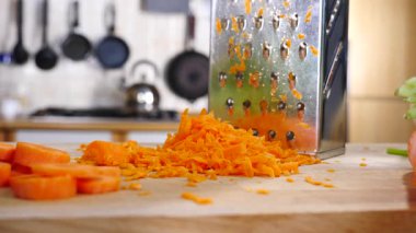 Izgarayı ve doğranmış havucu yavaş çekimde mutfak tahtasına yakın tut..