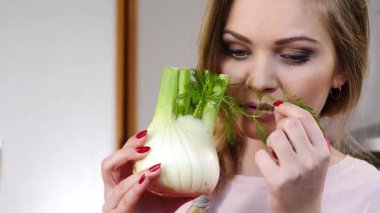 Çiğ sebze rezenesi tutan ve kokusunu alan mutlu genç bir kadın. Doğal organik sağlıklı gıda konsepti.