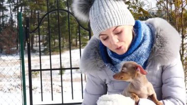 Genç bir kadın köpeğiyle oynuyor, pinscher ratter prazsky krysarik, kış havasında açık havada..