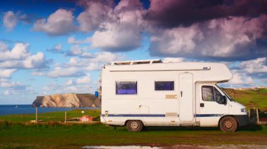 Kuzey İspanya 'nın Asterias sahilindeki Verdicio plajında kamp yapan bir kamp aracı. Cape Penas uçurumu uzakta. Karavanla git..