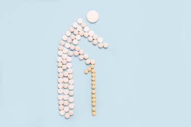 Mavi arka planda haplardan yapılmış bastonlu yaşlı bir adam.