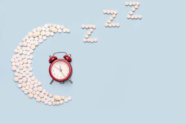 夕方の医療補助 概念不眠症 睡眠問題 月の形をした丸薬と青い背景の目覚まし時計 — ストック写真