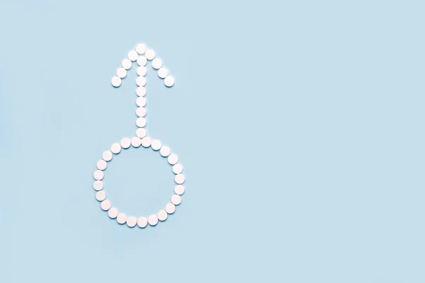 Medical pills in male symbol shape on a light blue background. Concept fmale health, contraception, fertility. Copy space