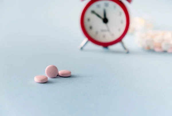 Time to take pills. Alarm clock  and pills on  blue background. Right time for using medicines