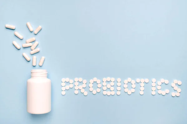 stock image Guts protection. Probiotics word made of pills, medicaments pills spilled from a white bottle. On blue background. 