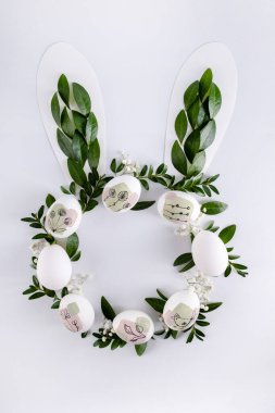  Beyaz zemin üzerinde doğal yeşil yapraklardan yapılmış tavşan kulakları ve daire şeklinde fotokopi alanı. Düz yatıyordu. Paskalya Minimum Konsepti