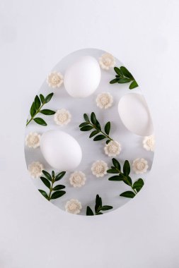 Paskalya kartı, kağıt kesilmiş yumurta şeklinde çerçeveli Paskalya yumurtası, bahar çiçekleri ve yeşil yapraklı. Düz yatış, üst görünüm