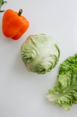 Peppers, lettuce, and cabbage on a white table