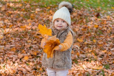 Mutlu çocuk parkta sarı yapraklarla oynuyor..