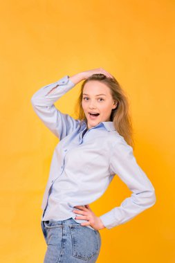 Mutluluk ve neşe duygusu. Mutluluk duygusuyla el ele tutuşan genç bir kadın, sürpriz, gömlek giymiş haberler ve sarı arka planda kot pantolon giymiş.