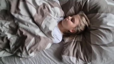Küçük kız uyuyor ve sabahları uyanıyor. Bir çocuğun sabah uyanması..