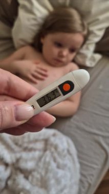 Suçiçeği olan hasta bir kızın arka planında termometre.