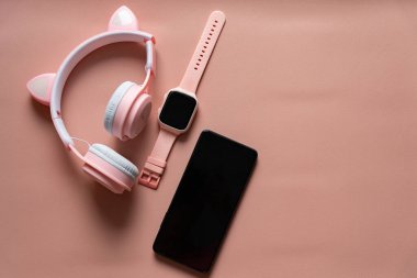 Pembe arka planda çocuk akıllı seti, telefon ve çocukların kablosuz kulaklıklarının modern cihazları. Teknoloji ve elektronik. Modern aygıtlar.