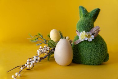Paskalya konsepti. Paskalya yumurtalı yeşil Paskalya tavşanı. Sarı arka planda mesaj için yeri var..
