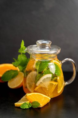 Siyah tahtada cam sürahi ve koyu bulanık arka planda portakal aromalı limonata. Yaz limonatasını tazeliyorum. Restoranlar ve kafeler için yaz içeceği kavramı.