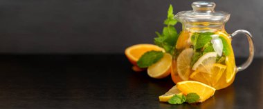 Üzerinde koyu bulanık bir arka planda cam bir sürahi portakal ve naneli limonata olan yazı için yeri olan pankart. Restoranlar ve kafeler için yaz içkileri konsepti.