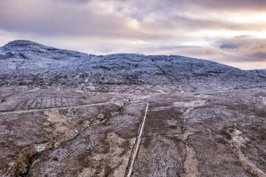 The R251 next to the snow covered Mount Errigal, the highest mountain in Donegal - Ireland