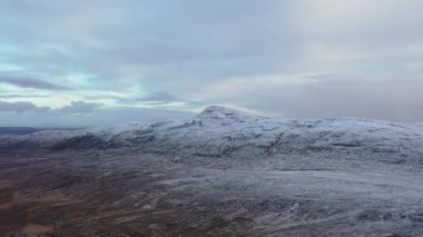 The R251 next to the snow covered Mount Errigal, the highest mountain in Donegal - Ireland