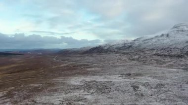 The R251 next to the snow covered Mount Errigal, the highest mountain in Donegal - Ireland