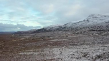 The R251 next to the snow covered Mount Errigal, the highest mountain in Donegal - Ireland