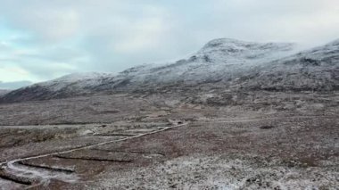 The R251 next to the snow covered Mount Errigal, the highest mountain in Donegal - Ireland